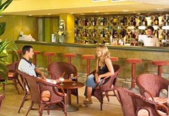 Bar scene at MS Aguamarina Suites, a gay-friendly hotel. A couple enjoys drinks. The bartender is ready to serve. Relaxed atmosphere.