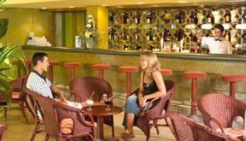 Bar scene at MS Aguamarina Suites, a gay-friendly hotel. A couple enjoys drinks. The bartender is ready to serve. Relaxed atmosphere.