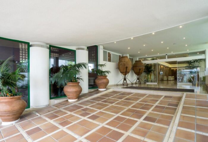 MS Aguamarina Suites, a gay-friendly hotel. Entrance with plants, terracotta pots, and tiled floor. Hotel H sign visible.
