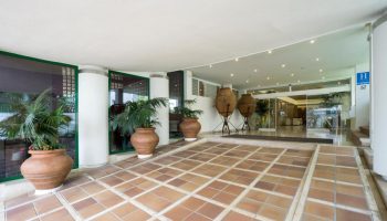 MS Aguamarina Suites, a gay-friendly hotel. Entrance with plants, terracotta pots, and tiled floor. Hotel H sign visible.