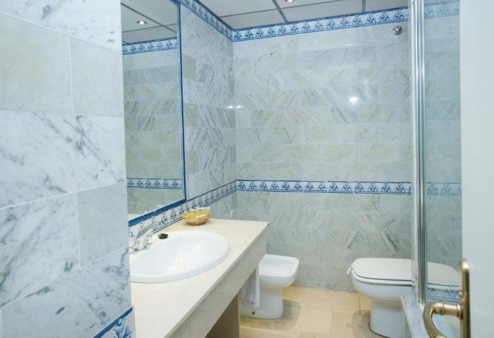 MS Aguamarina Suites gay-friendly hotel bathroom. Features marble tiles, a sink, toilet, and shower. Ideal for gay men's travel.