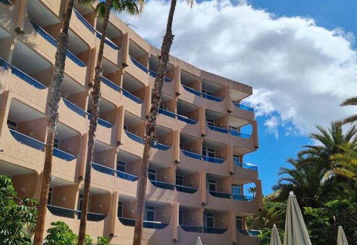 MUR Aparthotel Buenos Aires, Gran Canaria. Gay-friendly hotel exterior with palm trees, balconies, and poolside seating. Vacation vibes.