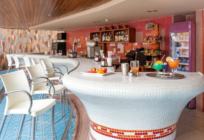 Bar at MUR Aparthotel Buenos Aires, Gran Canaria. Colorful cocktails, fruit, and spirits. Gay-friendly hotel bar with white mosaic counter.