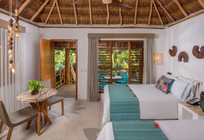 Mahekal Beach Front Resort & Spa room. Gay-friendly hotel with twin beds, thatched roof, balcony, and tropical view. Ideal for gay travel.