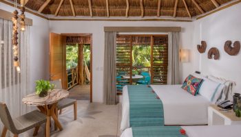 Mahekal Beach Front Resort & Spa room. Gay-friendly hotel with twin beds, thatched roof, balcony, and tropical view. Ideal for gay travel.