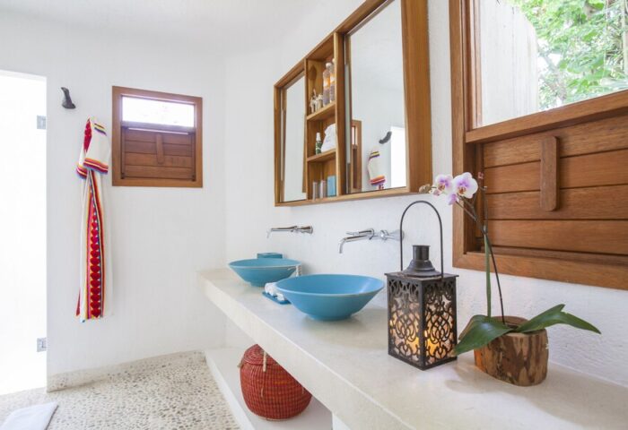 Bathroom at Mahekal Beach Front Resort and Spa, a gay-friendly hotel. Blue sinks, wood accents, and a lantern create a relaxing vibe.
