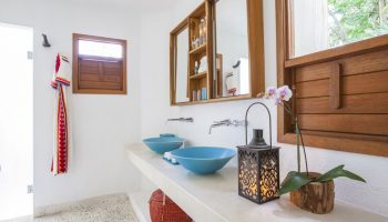 Bathroom at Mahekal Beach Front Resort and Spa, a gay-friendly hotel. Blue sinks, wood accents, and a lantern create a relaxing vibe.