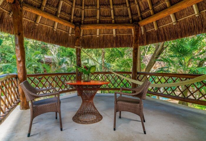 Mahekal Beach Front Resort and Spa palapa. Gay-friendly hotel with table, chairs, and hammock. Relaxing vacation spot for gay men.
