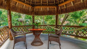 Mahekal Beach Front Resort and Spa palapa. Gay-friendly hotel with table, chairs, and hammock. Relaxing vacation spot for gay men.