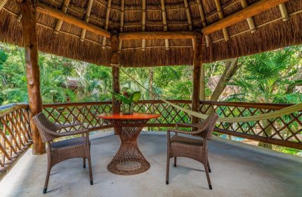 Mahekal Beach Front Resort and Spa palapa. Gay-friendly hotel with table, chairs, and hammock. Relaxing vacation spot for gay men.