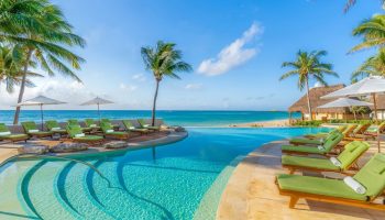 Mahekal Beach Front Resort and Spa pool view. Gay-friendly hotel with lounge chairs, palm trees, and ocean views. Ideal for gay men's travel.
