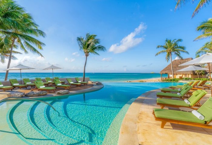 Mahekal Beach Front Resort and Spa pool view. Gay-friendly hotel with lounge chairs, palm trees, and ocean views. Ideal for gay men's travel.