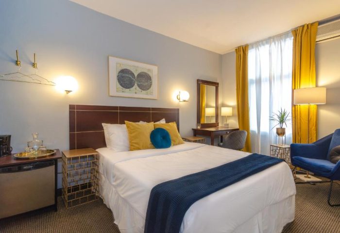 Maison Cartier Montreal gay-friendly hotel room. Queen bed, blue accents, desk, and yellow curtains. Upscale lodging for gay travelers.