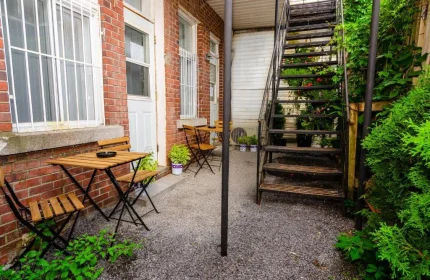 Maison Cartier Montreal: Outdoor patio area at this gay-friendly hotel. Tables, chairs, and greenery create a welcoming space. Metal stairs visible.