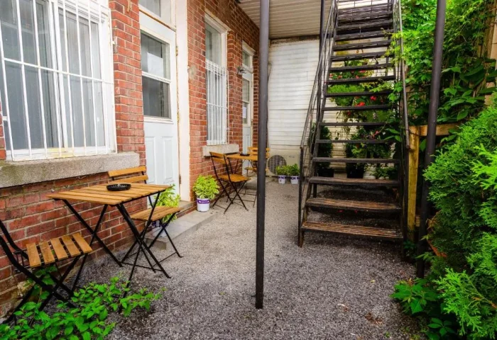 Maison Cartier Montreal: Outdoor patio area at this gay-friendly hotel. Tables, chairs, and greenery create a welcoming space. Metal stairs visible.