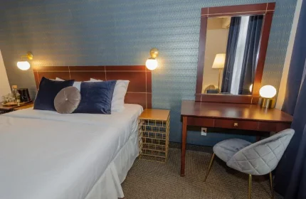 Maison Cartier Montreal gay-friendly hotel room. Bed with blue pillows, desk with mirror, and stylish decor for gay travelers.