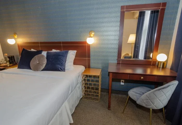 Maison Cartier Montreal gay-friendly hotel room. Bed with blue pillows, desk with mirror, and stylish decor for gay travelers.