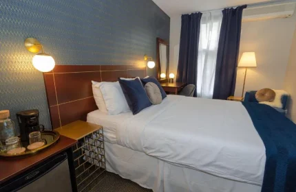 Maison Cartier Montreal gay-friendly hotel room. Queen bed with white linens, blue accents, desk, and lamps. Modern, comfortable lodging.