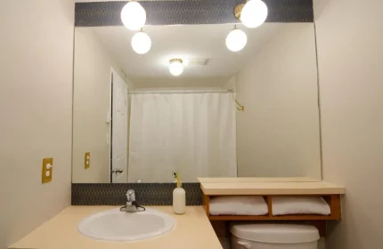 Bathroom at Maison Cartier, a gay-friendly hotel in Montreal. Features a sink, toilet, mirror, and shower.