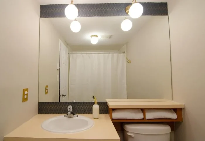Bathroom at Maison Cartier, a gay-friendly hotel in Montreal. Features a sink, toilet, mirror, and shower.