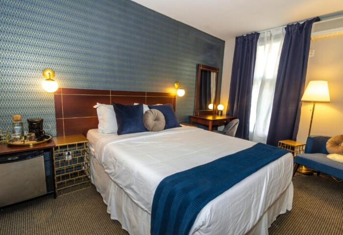 Maison Cartier Montreal gay-friendly hotel room. A bed with blue accents, desk, and sitting area. Upscale lodging for gay travelers.