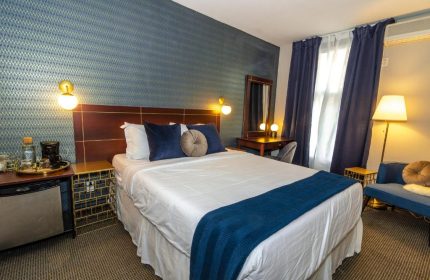 Maison Cartier Montreal gay-friendly hotel room. A bed with blue accents, desk, and sitting area. Upscale lodging for gay travelers.