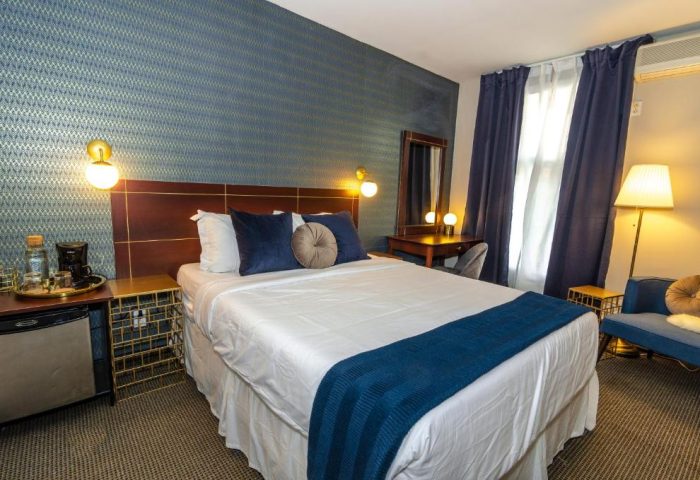 Maison Cartier Montreal gay-friendly hotel room. A bed with blue accents, desk, and sitting area. Upscale lodging for gay travelers.