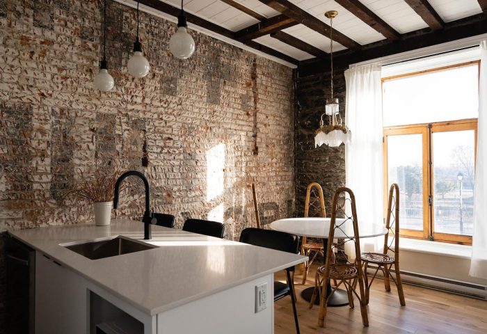 Maison Place Royale kitchen by Luxury In Transit. Gay-friendly hotel interior with brick wall, island, and dining table.