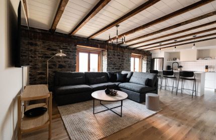 Maison Place Royale living area. Gay-friendly hotel by Luxury In Transit features exposed stone walls, wood beams, and modern kitchen.