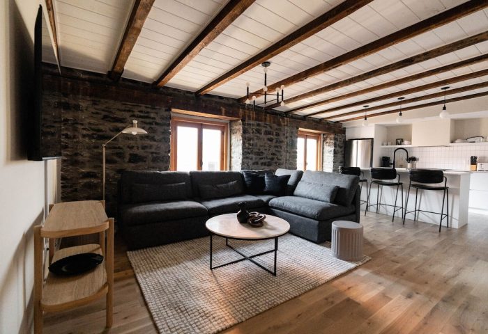 Maison Place Royale living area. Gay-friendly hotel by Luxury In Transit features exposed stone walls, wood beams, and modern kitchen.