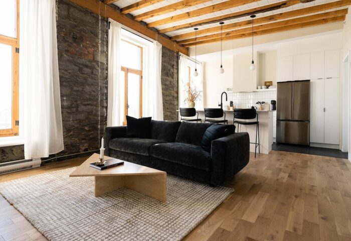 Maison Place Royale living space. Gay-friendly hotel by Luxury In Transit features exposed brick, wood beams, and modern kitchen.