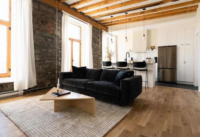 Maison Place Royale living space. Gay-friendly hotel by Luxury In Transit features exposed brick, wood beams, and modern kitchen.