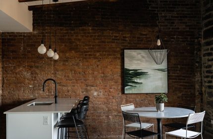 Maison Place Royale interior. Gay-friendly hotel with exposed brick, modern lighting, kitchen island, and dining area. Luxury In Transit travel.
