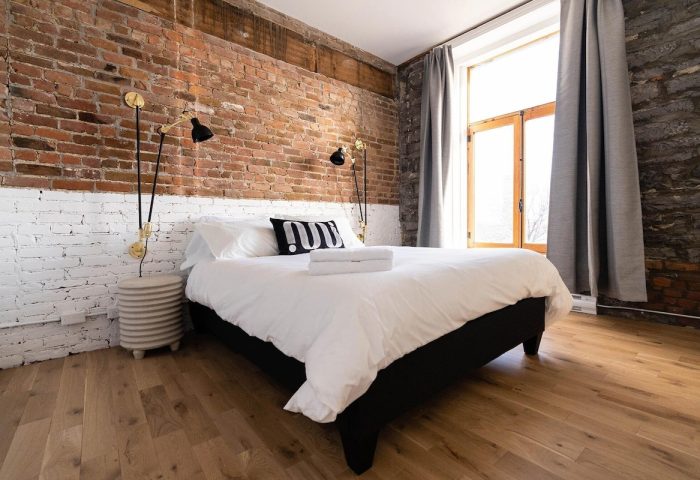 Maison Place Royale hotel room with brick wall, bed, and window. Gay-friendly luxury travel in Quebec City, Canada.