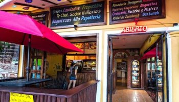 Maison Tulum gay-friendly hotel cafe. Open sign, menu boards, and outdoor seating. Crepes, salads, pastries, and Mexican breakfast options.