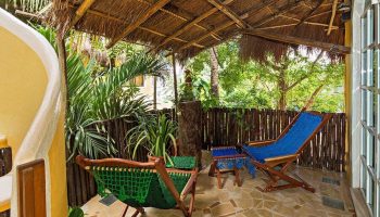 Maison Tulum gay-friendly hotel patio. Tropical getaway with comfy chairs, lush plants, and a thatched roof. Relaxing Tulum vibes.
