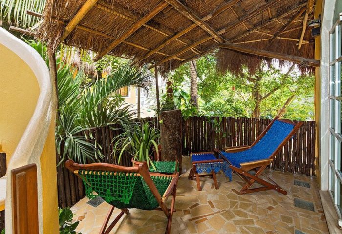 Maison Tulum gay-friendly hotel patio. Tropical getaway with comfy chairs, lush plants, and a thatched roof. Relaxing Tulum vibes.