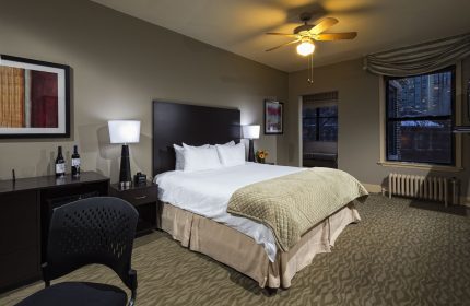 Majestic Hotel Chicago guest room. Gay-friendly hotel features a king bed, wine, city views, ceiling fan, and warm, inviting decor.