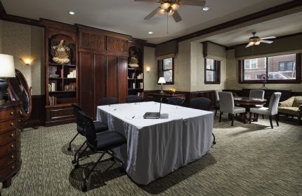 Meeting room at the gay-friendly Majestic Hotel Chicago. Table with laptop, chairs, ceiling fans, and bookshelves. Interior view.