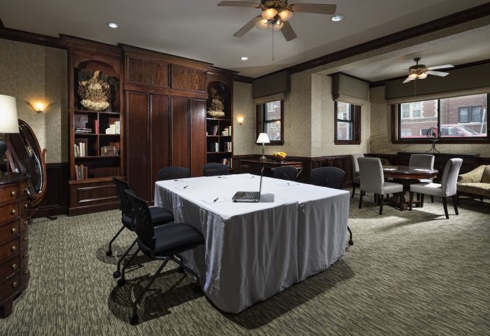 Meeting room at the gay-friendly Majestic Hotel Chicago. Table with laptop, chairs, ceiling fans, and bookshelves. Interior view.