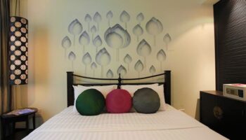Makka Hotel room: bed with floral wall art, round pillows. Gay-friendly hotel with safe. Ideal for gay men travel. Comfortable & stylish.