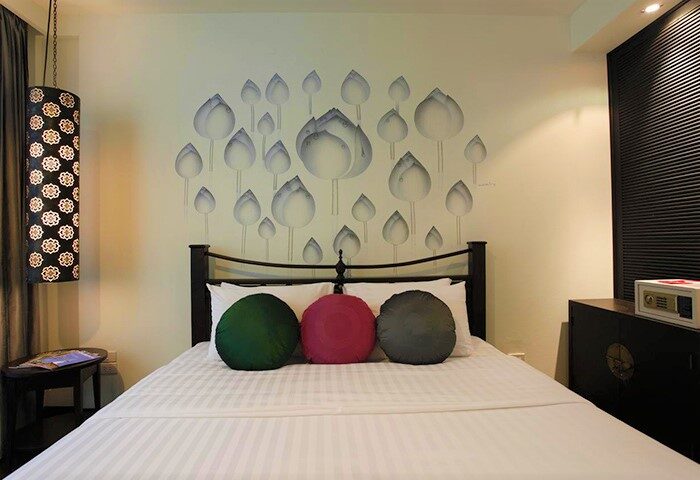 Makka Hotel room: bed with floral wall art, round pillows. Gay-friendly hotel with safe. Ideal for gay men travel. Comfortable & stylish.