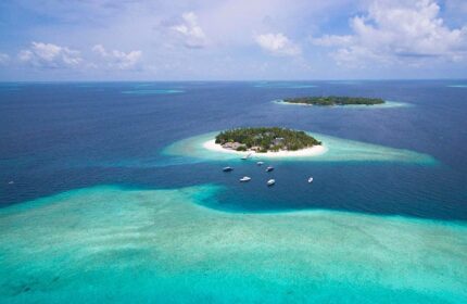 Aerial view of Malahini Kuda Bandos Resort, a gay-friendly hotel in the Maldives. Turquoise water, white sand beach, and tropical island.