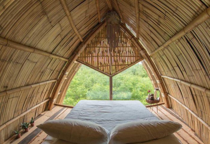 Mamasan Treehouses & Cabins interior. Gay-friendly hotel room with bamboo walls, bed, and view of trees. Unique cabin for gay travel.