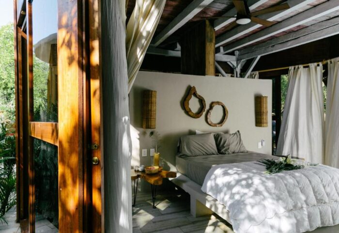 Mamasan Treehouses & Cabins gay-friendly hotel room. Interior view of a cabin with a bed, bedside table, and rustic decor. Perfect for gay travel.