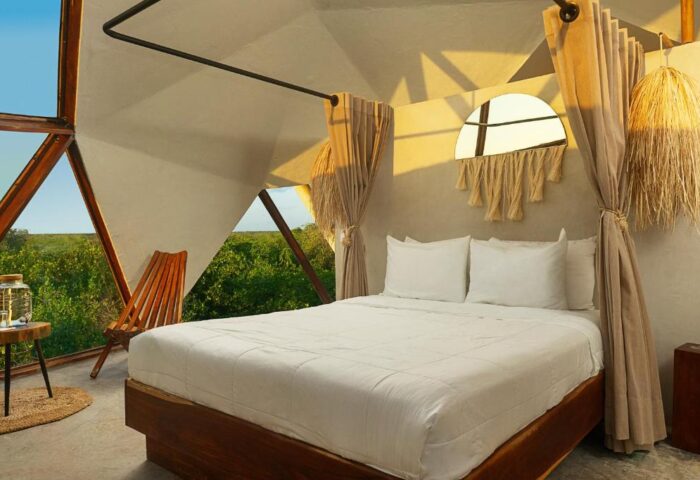 Mamasan Treehouses & Cabins interior. View of a bed, chair, and jungle from inside a gay-friendly hotel treehouse. Cabins offer unique stays.