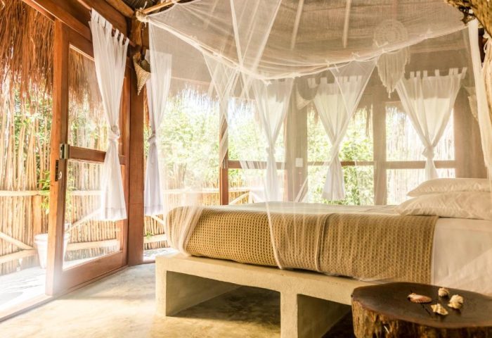 Mamasan Treehouses & Cabins gay-friendly hotel: bedroom with mosquito net, white curtains, and wooden accents. Perfect for gay men travel.