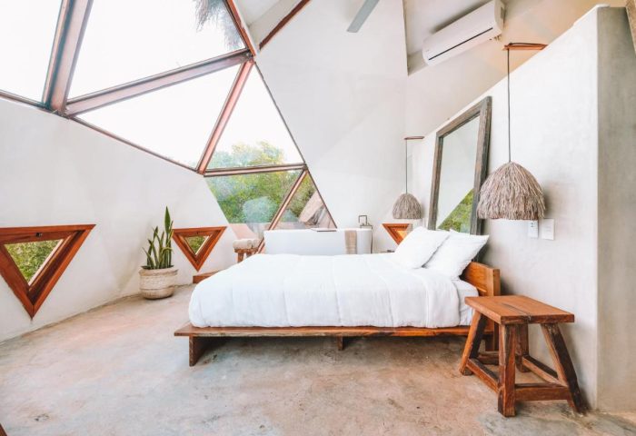 Mamasan Treehouses & Cabins bedroom. Gay-friendly hotel room with triangle windows, white linens, and modern design. A relaxing getaway.