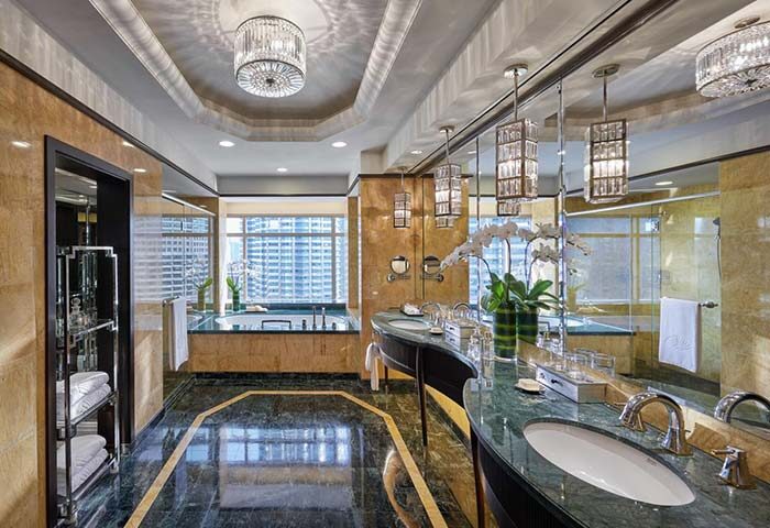 Gay-friendly Mandarin Oriental Kuala Lumpur hotel bathroom. Marble floor, double sinks, bathtub with city view, & crystal chandeliers.
