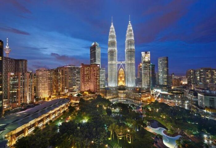 Kuala Lumpur skyline at dusk. Petronas Towers view from Mandarin Oriental, a gay-friendly hotel in Kuala Lumpur. Cityscape with park.